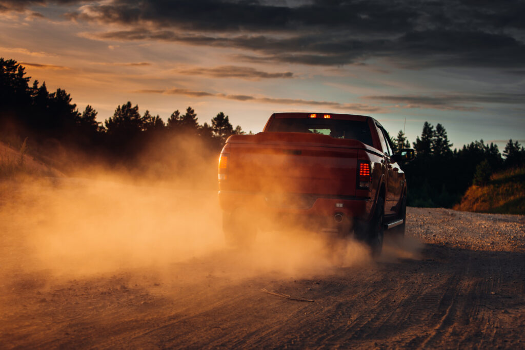 Pickup truck in motion on a country road with clouds of dust. An