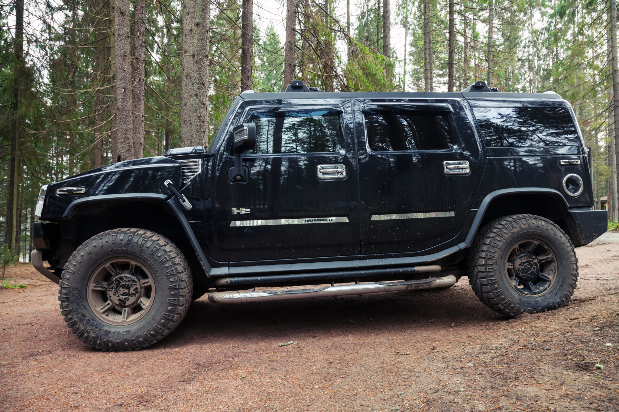 Black Hummer H2 vehicle stands on dirty country road